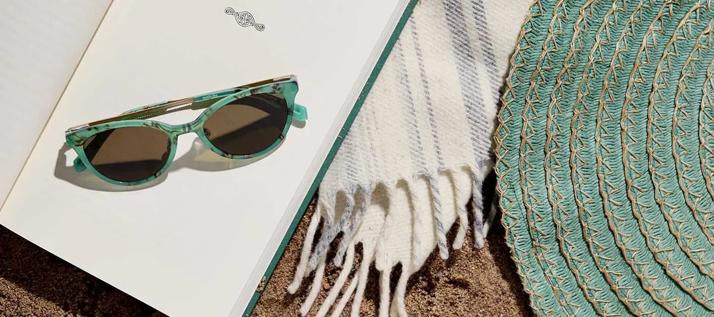 glasses on an open book next to a sun hat