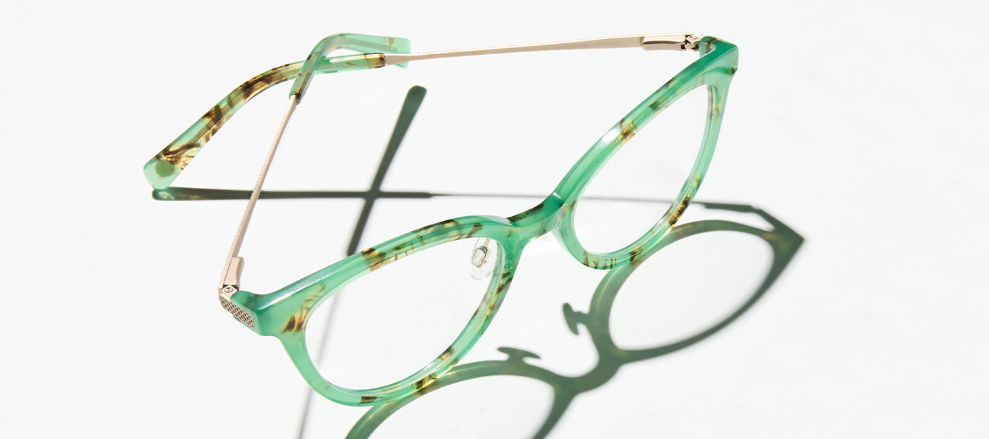 green frame eyeglasses on a clear counter top
