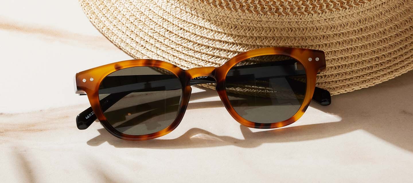turtle shell sunglasses next to a straw hat