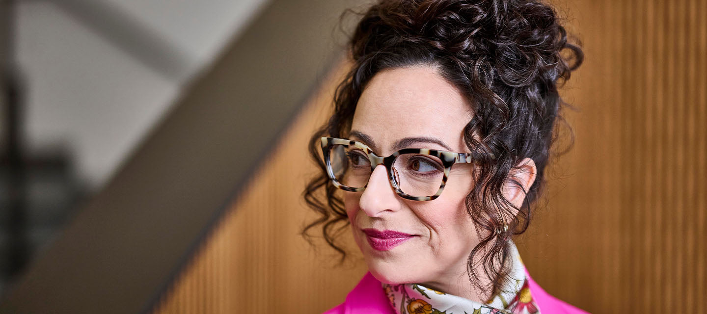 woman with curly done-up hair looking to the side wearing tortoise shell glasses