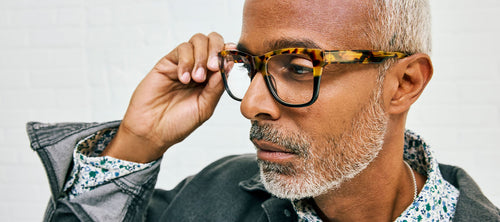 man holding hand up to adjust tortoise shell frames