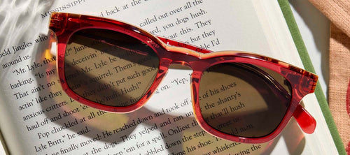 sunglasses resting on an open book with text showing through