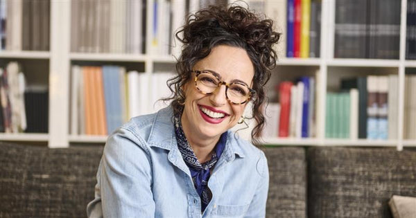 woman with curly brown hair smiling in front of a book shelf