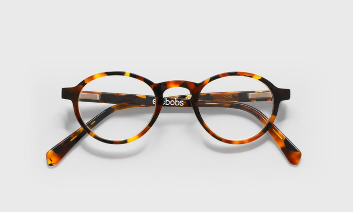19_eyebobs premium designer board stiff readers, blue light and prescription glasses in tortoise front and temples, laydown