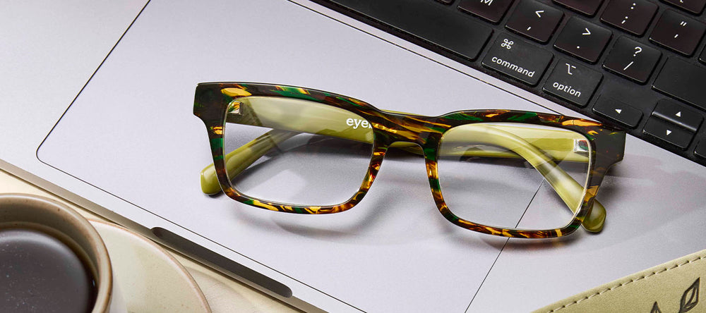 Rectangular reading glasses with Italian-designed acetate frames in green tortoiseshell resting on a laptop keyboard
