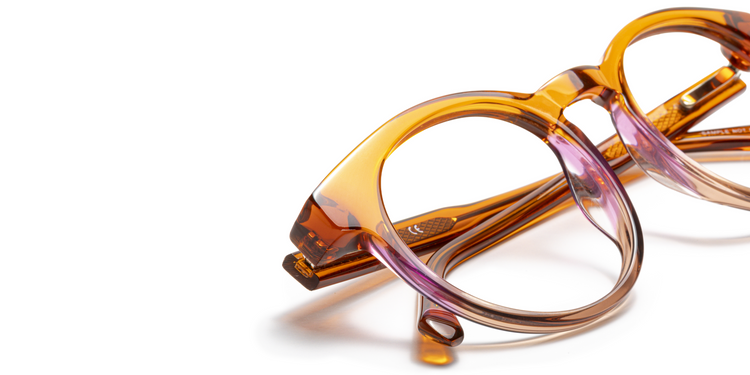 Close-up of Italian-designed acetate reading glasses with a warm amber to soft purple gradient and smooth polished finish