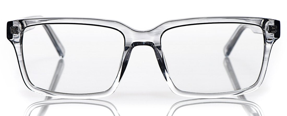 Wide transparent grey acetate rectangular eyeglasses with wide frames and a glossy finish on a reflective white surface