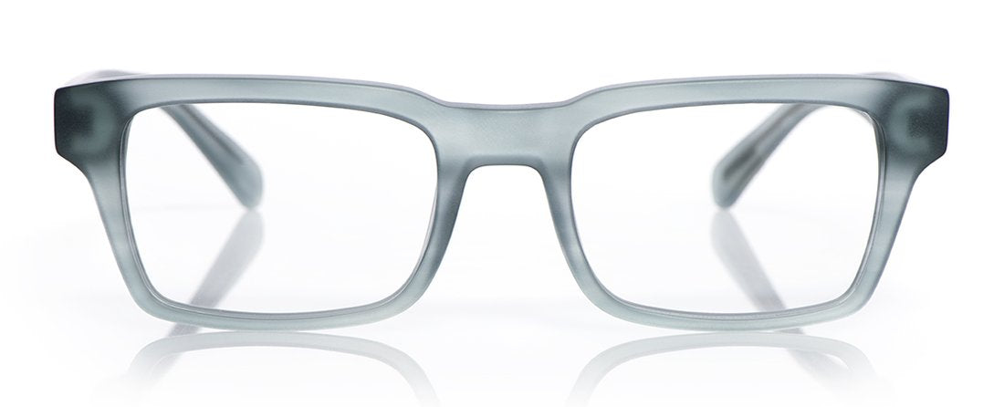 Wide unisex square eyeglasses with translucent smoky gray acetate frame and subtle matte finish on reflective white surface