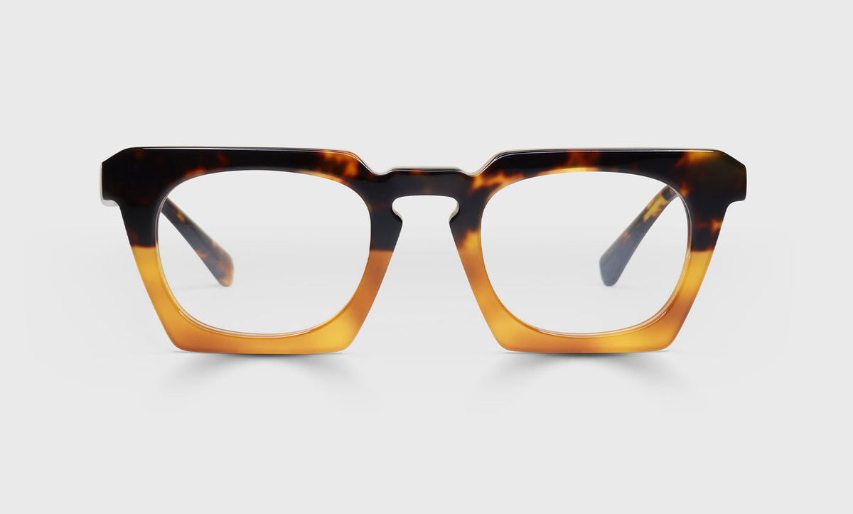Wide geometric prescription glasses with tortoise fade front blending dark and amber tones and tortoise temples on white background