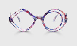 Round eyeglasses with rose, violet, and cobalt watercolor frames disrupted by clear geometric shapes on light gray background