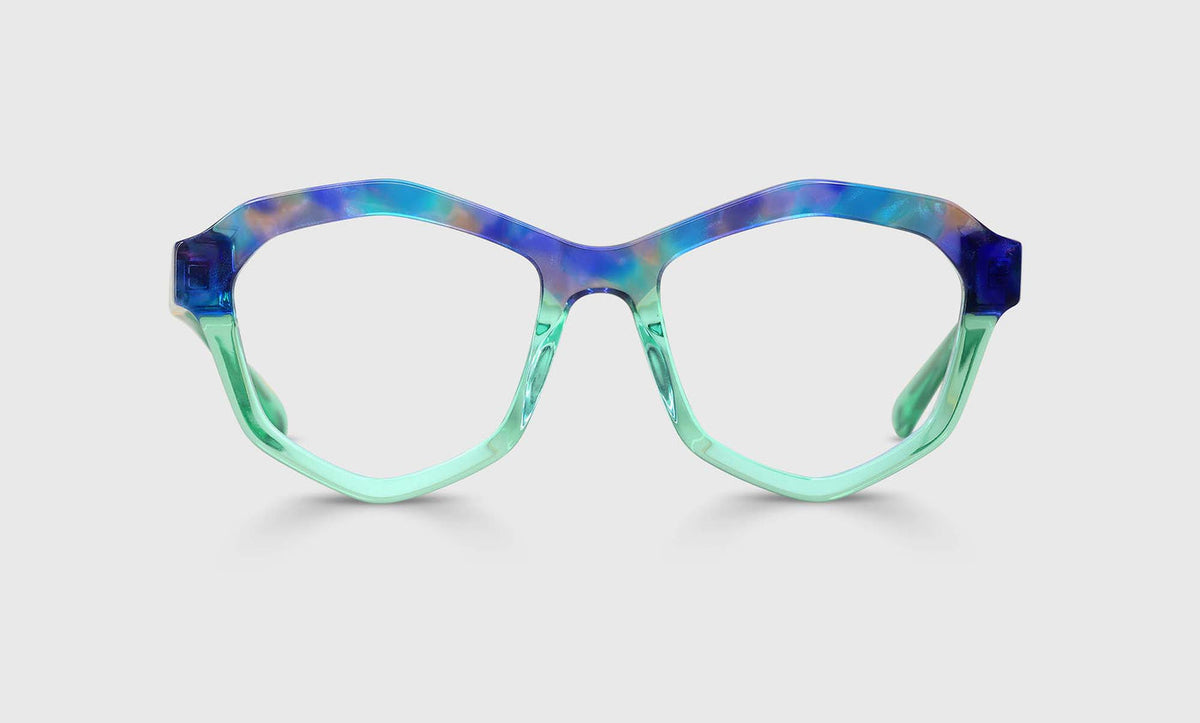 Geometric acetate eyeglasses in blue-purple tortoise top frame with translucent sea glass lower front and temples on gray background