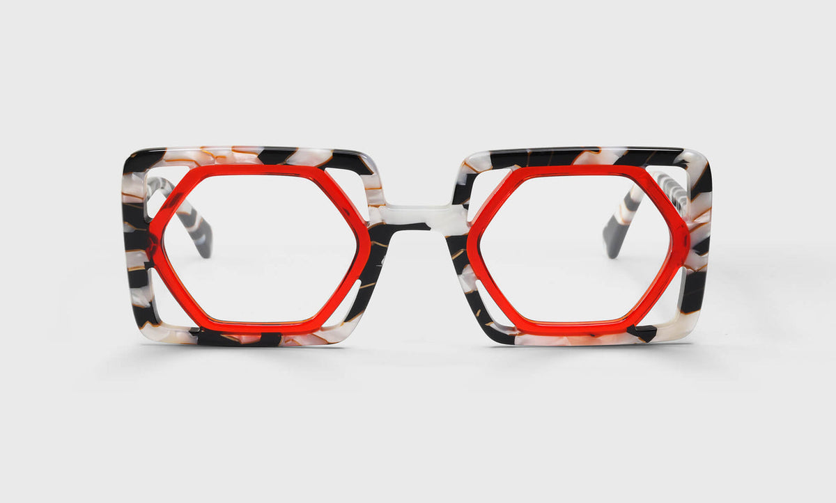 Oversized hexagonal eyeglasses with vibrant warm crimson inner frame and black and white marble textured outer rims on white background