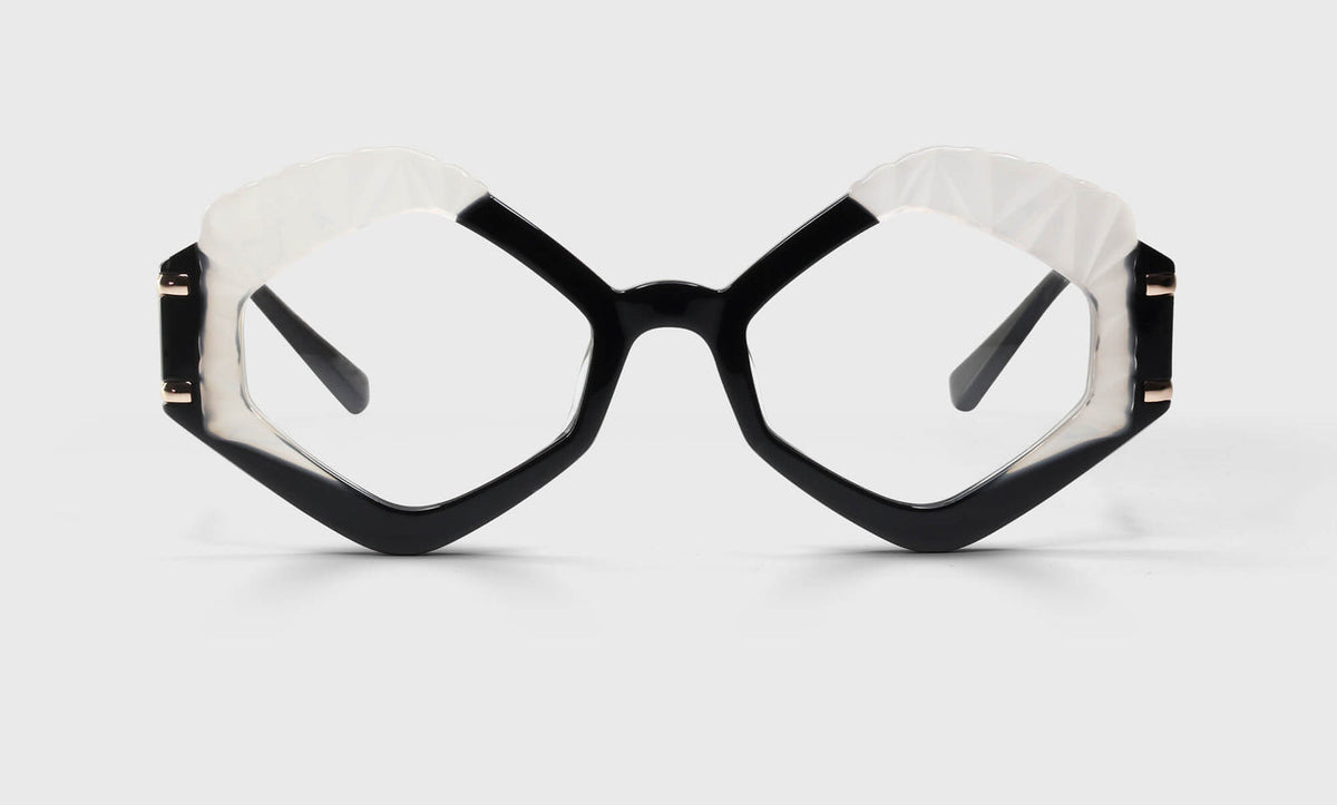Angular eyeglasses with bold black and white frames and polished stainless steel temples on a neutral background